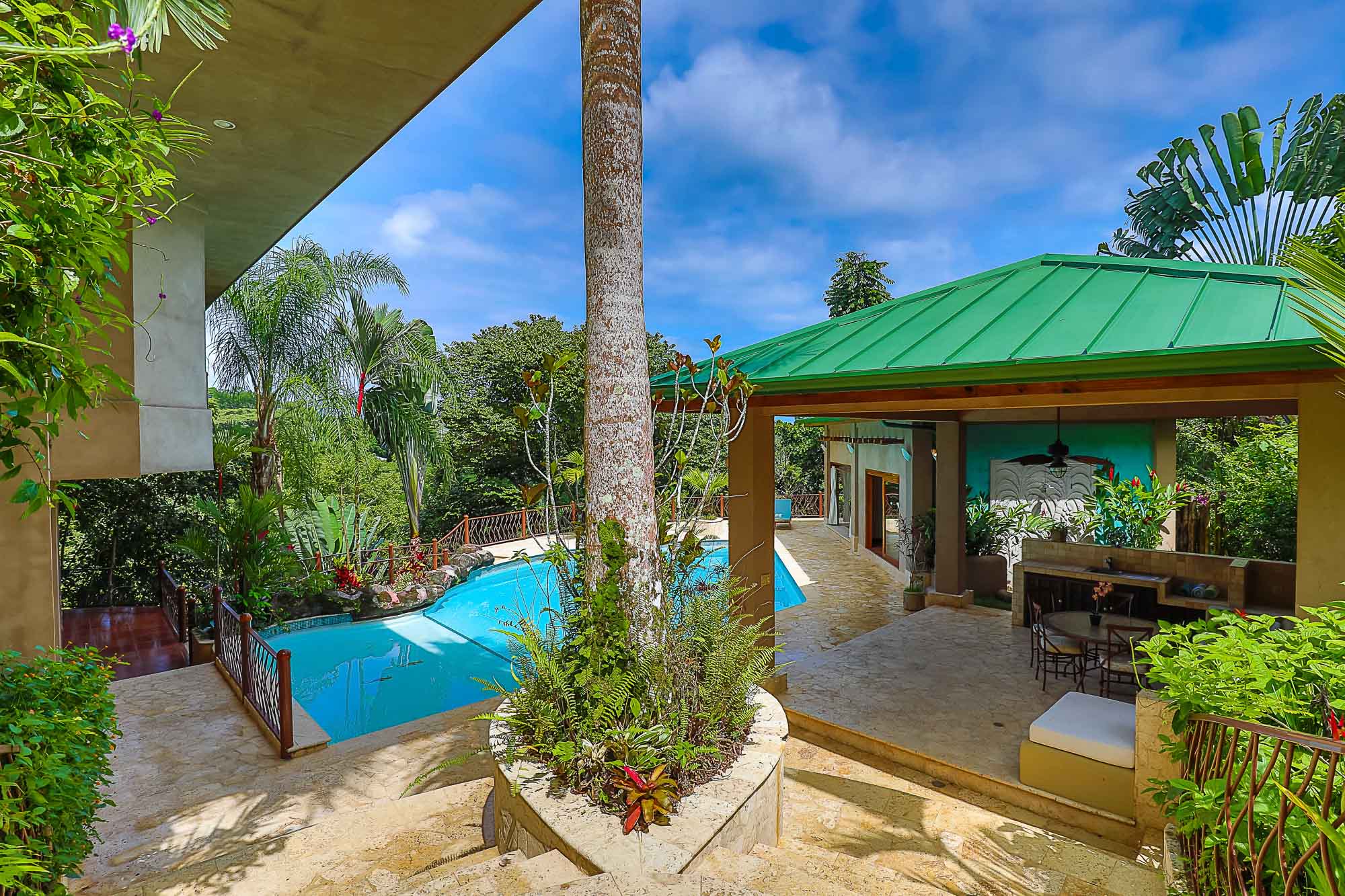 A bright blue pool and a covered outdoor pavilion and lounge area perfect to enjoy under a clear, sunny sky.