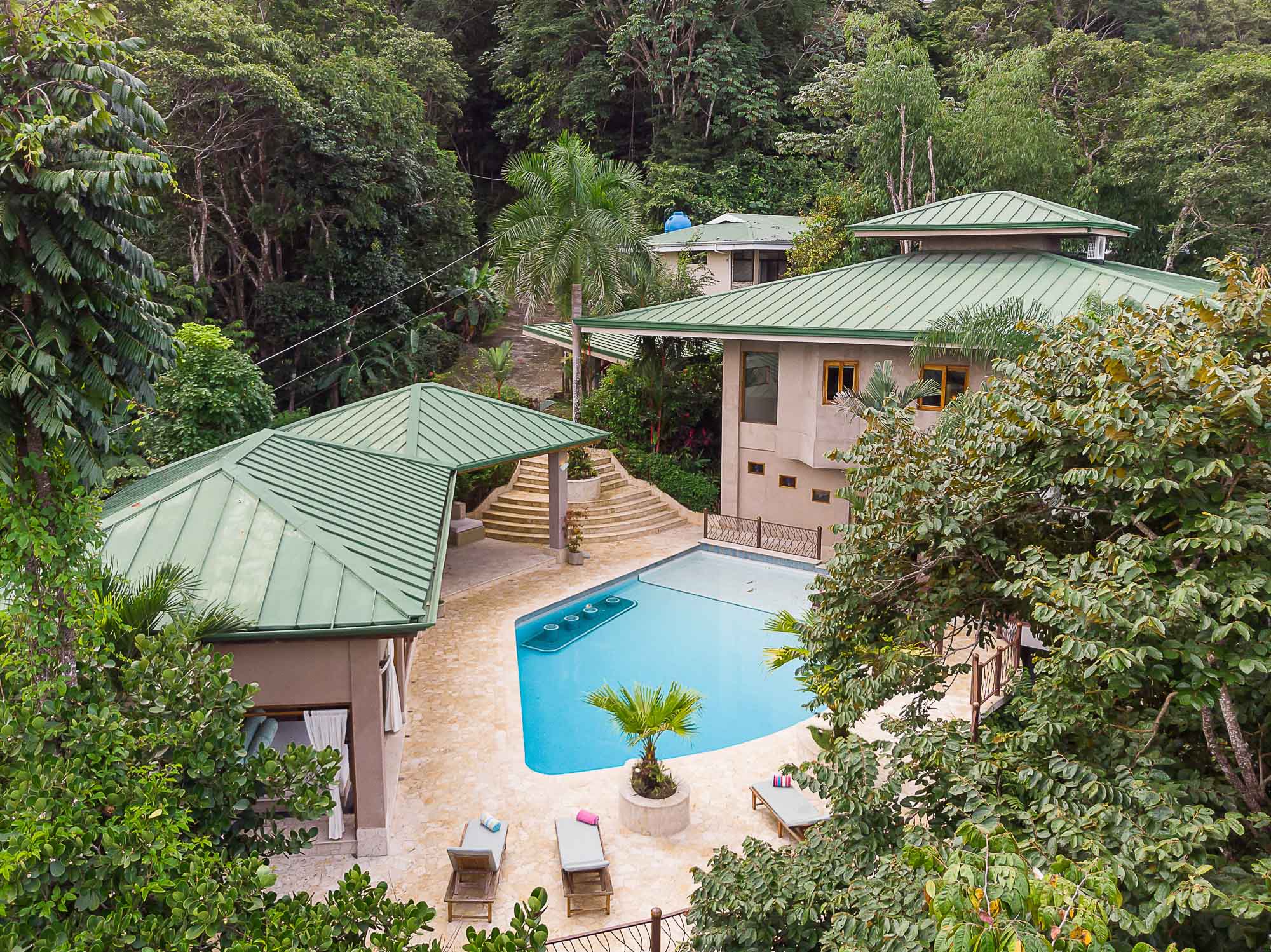 The Estrella del Mar villa complex features a large pool and patio bordered by a lush tropical rainforest.