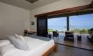 Un dormitorio luminoso cuenta con una cama king y amplias puertas de vidrio que abren a una terraza privada, ofreciendo vistas directas al océano y abundante luz natural.